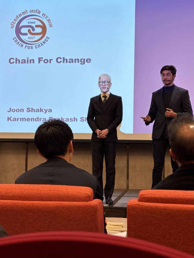 Project Secretary Karmendra Shrestha is giving answer to the question being posed by the jury. Project lead Joon Shakya is standing beside him and on the background CFC logo is being presented and the names of Joon Shakya and Karmendra Shrestha is being displayed just below.