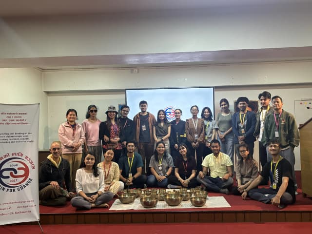 A group picture of around 25 individuals including CFC members, new project members along with Mr. Oscar. On the left, CFC banner is seen and in front Singing bowls are placed.