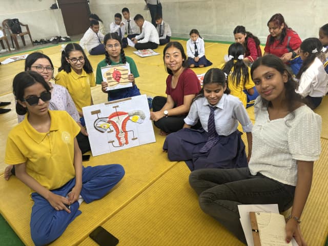 A group picture of 4 female students with visual disabilities and 3 of the project members who are holding both the accessible 3D models of inner and external female reproductive system. In the background other groups of the workshops are also observed.