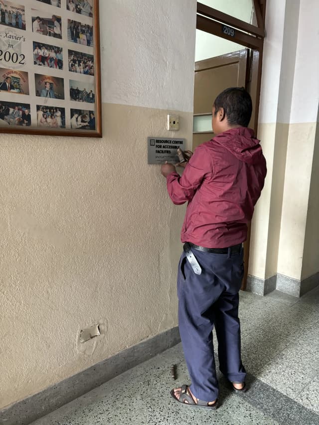 One of the technical staff from St. Xavier's College, Maitighar is installing the accessible signboard of Resource Centre for Accessible Facilities.