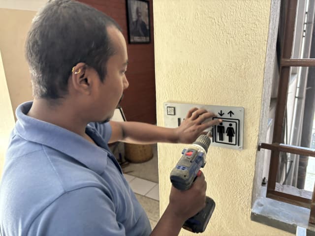 One of the technical staff from St. Xavier's College, Maitighar is installing the accessible signboard of lift.