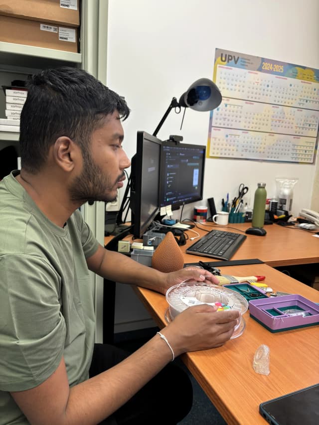 Our Founder Abhishek Shahi is touching the flexible filament. In the table, there are many materials placed on the office table and in background there is a computer.