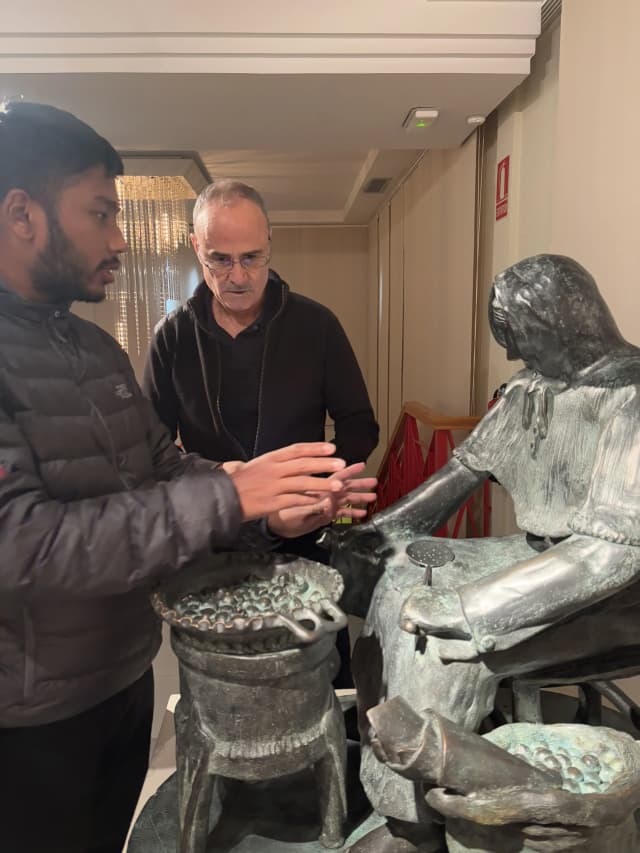 Our Founder Abhishek Shahi is touching The sculpture 'Escultura Táctil' (Tactile Sculpture) by José Royo. In the background, Danny is explaining him about it. The artwork represents a woman, likely engaged in a traditional or everyday activity, sitting with a container or vessel placed in front of her.